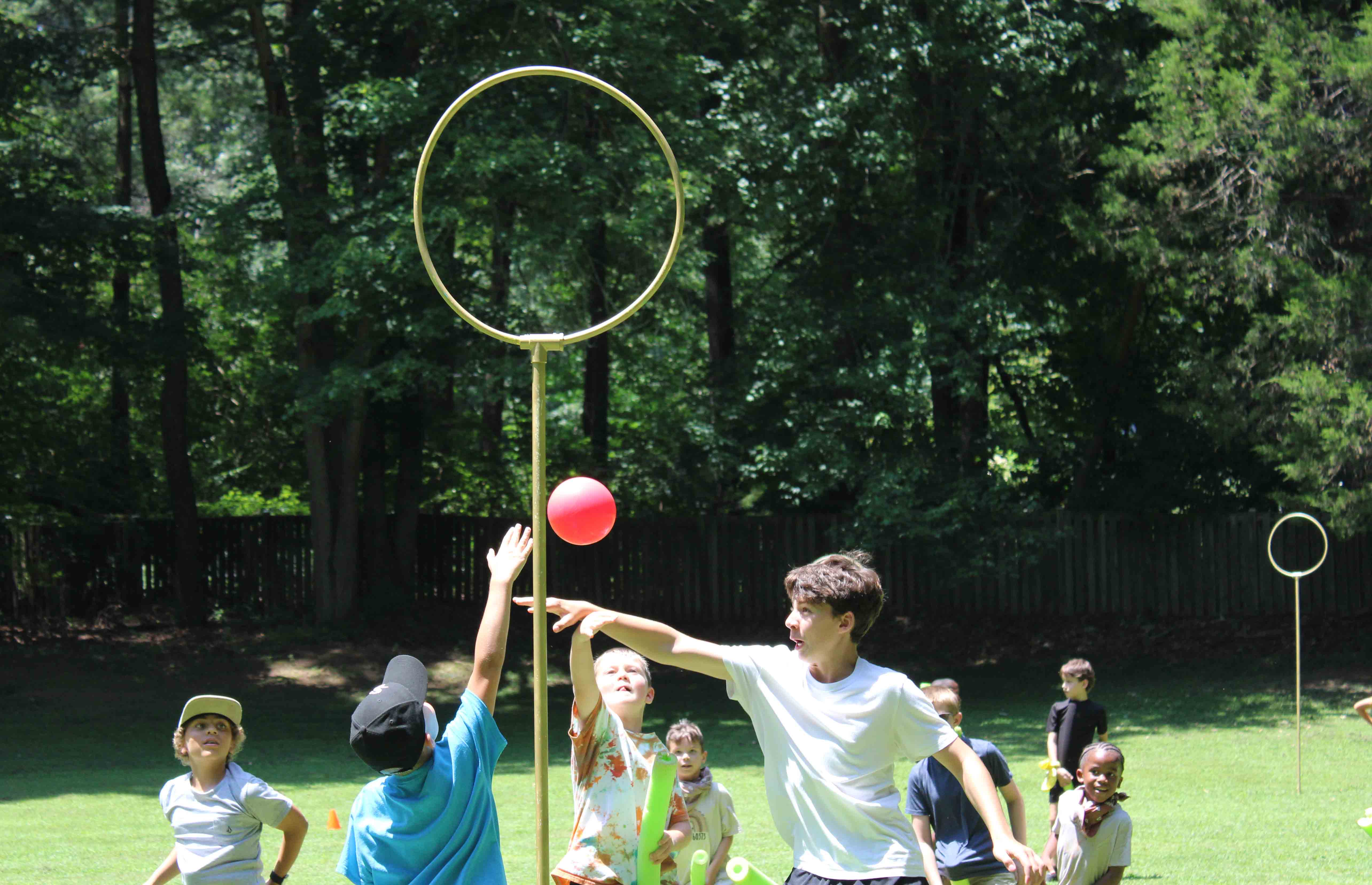 Rangers unit campers playing a lively game of Quidditch out on the sports field near a gold scoring hoop.