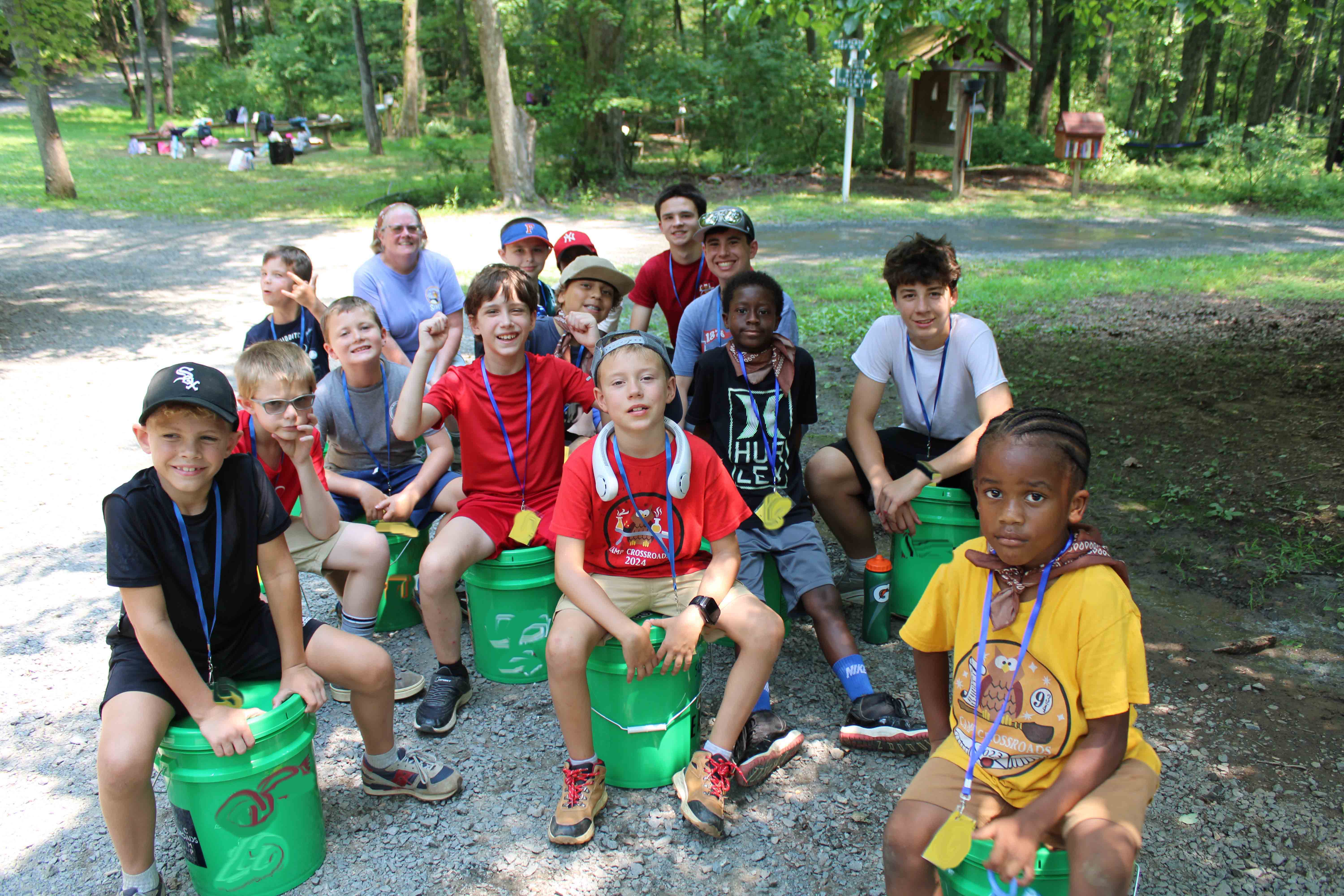 Campers on the challenge course leaning over a wooden wall to assist their teammates.