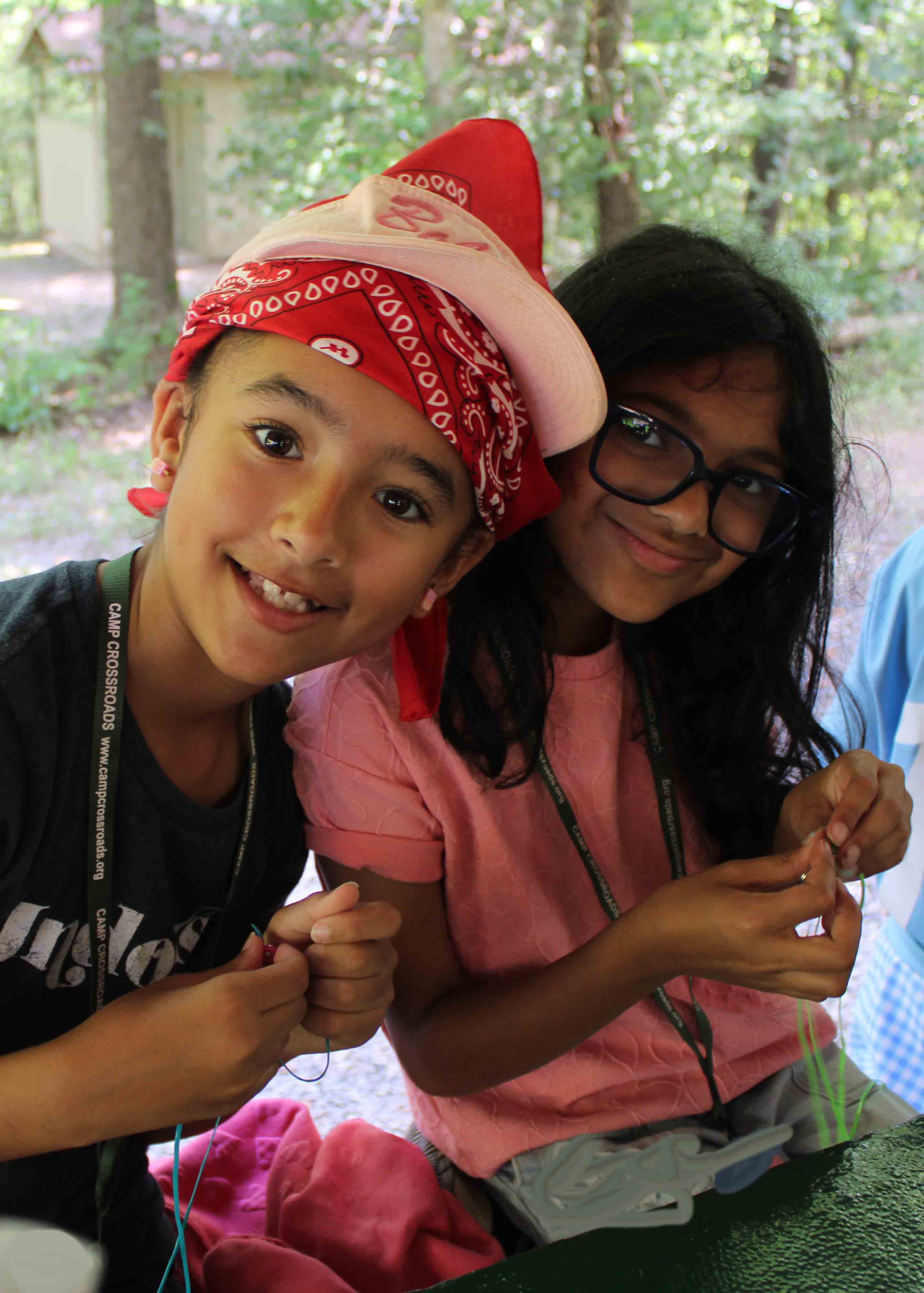 Two campers from the Tornadoes unit smiling and laughing during an indoor craft activity.